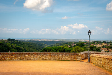 Panorama toscano con borgo collinare e lampione su muro in pietra