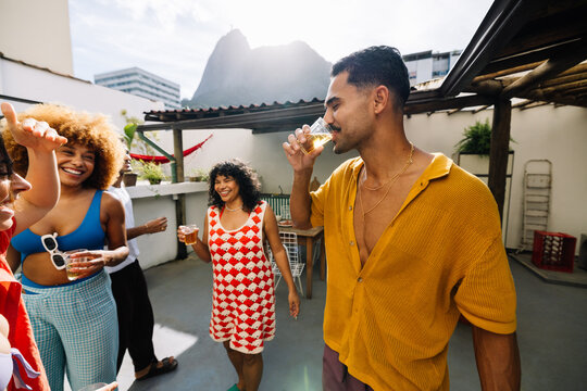 Group of friends enjoying outdoor rooftop drinks and celebration under the sun