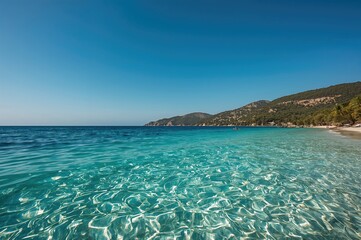 Fototapeta premium Wide view of a tropical beach with clear blue waters and mountainous background