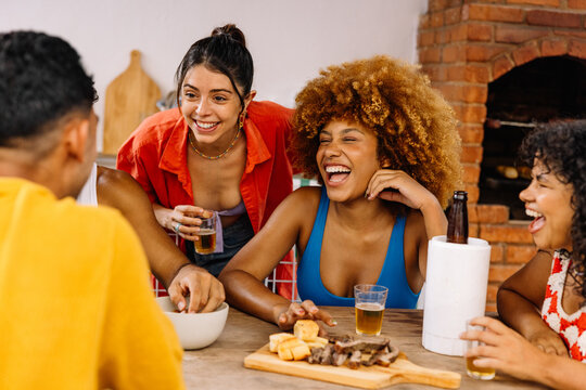 Brazilian friends laughing and drinking together at barbecue table - Powered by Adobe