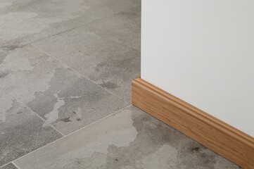 Detailed shot of a chic floor changeover featuring tile and smooth wood trim in a modern interior, emphasizing contemporary aesthetics