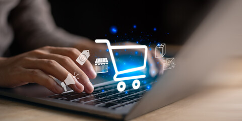 Typing on laptop with glowing shopping cart icon and digital marketing symbols, representing e-commerce, online shopping, product promotion, global marketplace connectivity for modern business growth.