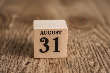 Handcrafted wooden block showing date and month alongside an hourglass filled with green sand symbolizing the flow of time. Artistic summer theme representing the day's progression.