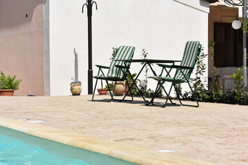 Countryside house with swimming pool in Italy. Relaxing in swimming pool. Summer and vacation background. Chairs with table near swimming pool. Healthy leisure lifestyle travel and exercise. 
