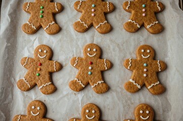 Freshly baked gingerbread figures and comet shapes on parchment, cooling before holiday decorating