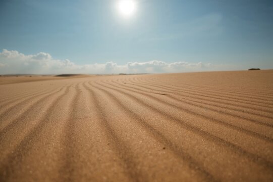 Detailed view of wavy sand patterns on dunes under a bright blue sky