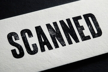 Close up of the word scanned in bold black letters on a white textured surface for document processing