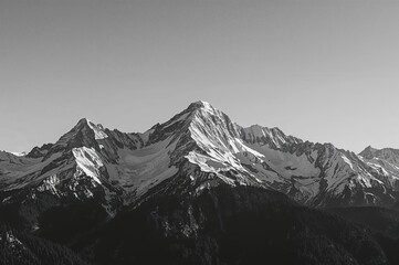 Obraz premium A striking monochrome photograph displaying towering snow-covered mountains beneath a pristine sky, evoking feelings of wonder and magnificence