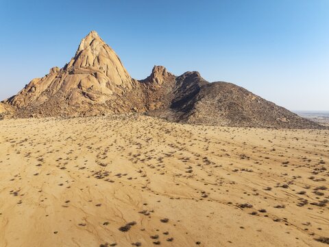 The isolated Spitzkoppe mountain (1728 m) majestically rises above the surrounding desert plains. Aerial view. Drone shot. Damaraland, Namibia