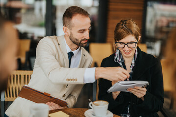 Mentor and mentee sitting at an outdoor cafe discussing ideas. A collaborative and professional coaching moment with friendly interaction.