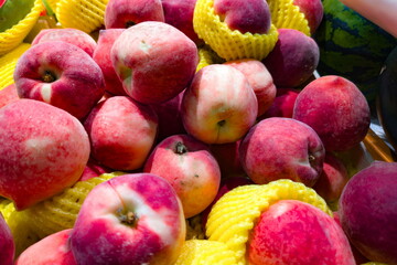 Colorful display of fresh peaches surrounded by vibrant yellow mesh in a market stall during the summer season