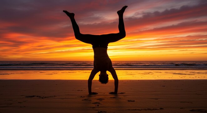 Silhouette of a man doing handstand on the beach during sunset