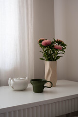 A Charming Floral Arrangement Styled with a Modern Teapot and a Matching Cup for Elegance
