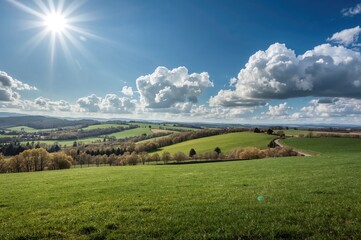 Fototapeta premium Picturesque rural landscape with green fields and a clear blue sky on a sunny spring afternoon.