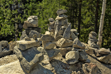 Hand-made stone pyramids of different sized and shaped stones against a green forest backdrop.  