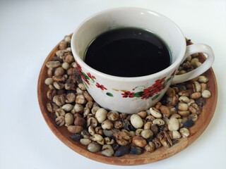 A cup of coffee inside the coffee beans on a wooden plate. Flat lay composition on a white background.