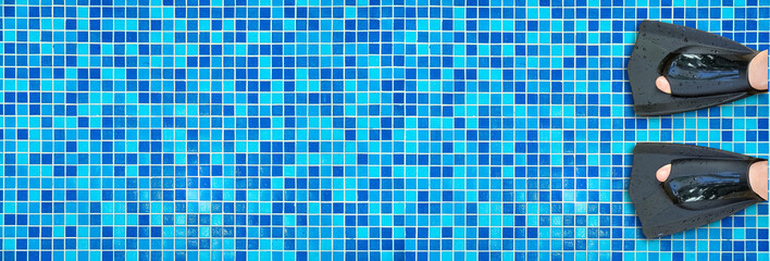 Banner of person wearing black swim fins in a swimming pool with blue mosaic tiles. Concept of summer, vacation, swimming, sport, and underwater activities © Pihuliak