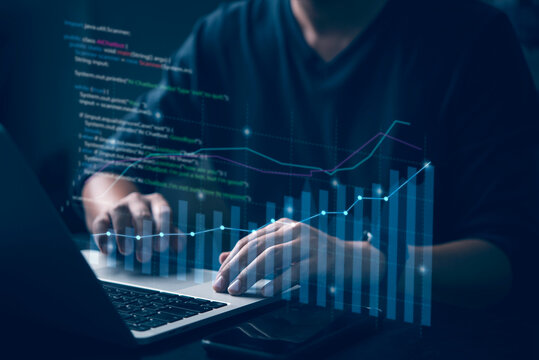 Business analyst using laptop with financial graphs and code overlay, concept of data analytics, fintech, stock market growth, big data, and digital business technology.