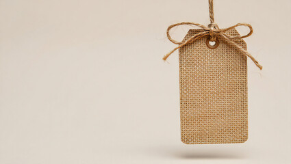 Elegant Burlap Tag with Jute Twine Bow Hanging on Neutral Background Perfect for Crafts Product Presentation and Rustic Style Mockups with Ample Copy Space
