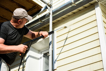 Cleaning the vinyl siding wall with a high-pressure washer.