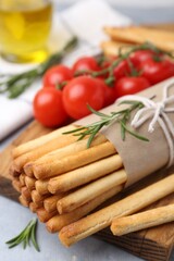 Delicious grissini sticks and rosemary on grey table, closeup