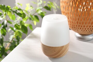 Modern aroma lamp on white wooden table indoors, closeup