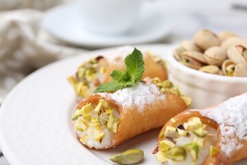 Delicious cannoli with cheese, pistachios, powdered sugar and mint on table, closeup