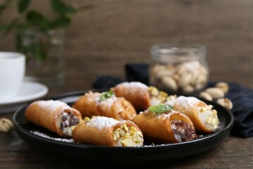 Delicious cannoli with cheese, nuts, powdered sugar, chocolate and mint on wooden table, closeup