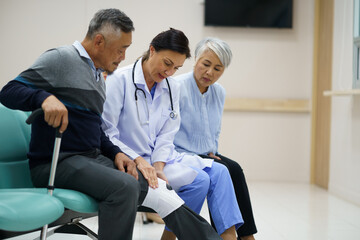 Obraz premium A doctor is helping an elderly man with his leg. The doctor is wearing a white coat and the man is wearing a gray sweater. A man suffered a broken leg. The scene is set in a hospital room.