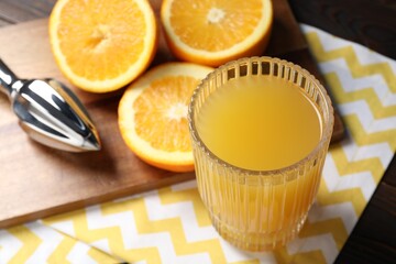 Freshly squeezed orange juice, fruits, juicer and towel on wooden table, closeup