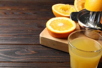 Freshly squeezed orange juice, fruits and juicer on wooden table, closeup. Space for text