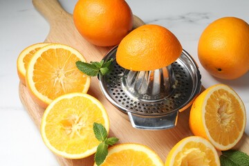 Squeezer with oranges and mint on white table, closeup. Making fresh juice