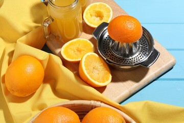 Squeezer, oranges and fresh juice on blue wooden table, closeup