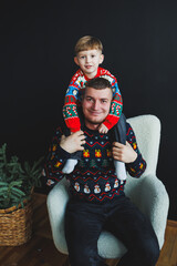A Joyful Holiday Portrait of a Loving Father and His Son in Festive Sweaters, Capturing Their Unique Bond and the Spirit of the Season Together, Filled with Happiness and Cheerful Energy