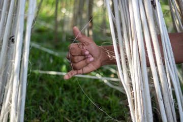 A hand forms the shaka sign amidst natural fibers in a field