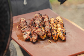 Juicy skewered meat grilled on a board and ready to eat during barbecue with smoke rising