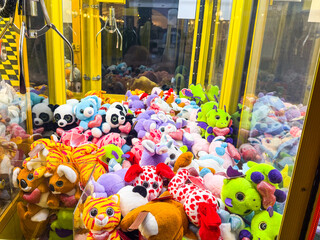 Claw machine filled with colorful stuffed animals and toys. Entertainment, leisure, childhood and amusement in an indoor arcade setting.