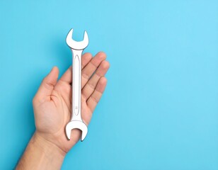 Hand holding a wrench against a bright blue background