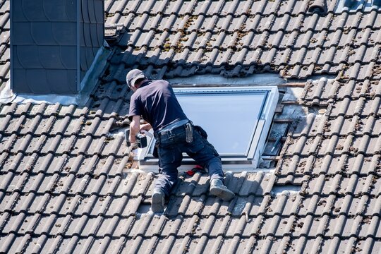 Roofers working on a roof installing a skylight