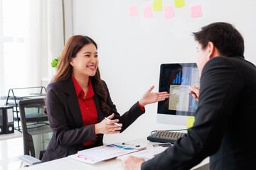 Asian businesspeople discussing marketing strategy showing charts on computer screen in the office