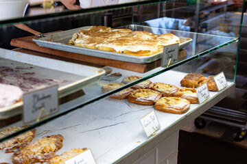 Bakery display case filled with various fresh French pastries including apple crumble danish, cinnamon rolls, and almond croissants