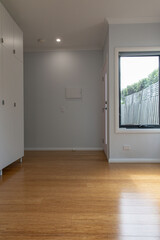 View of a minimalist room with light wood floors, built-in white wardrobe cabinets, and natural light from a nearby window, creating an uncluttered modern space