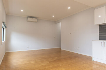 Spacious unfurnished living room with wooden flooring, soft gray walls, split system air conditioning and recessed ceiling lights