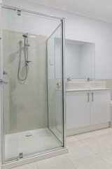 Modern bathroom with a glass-enclosed shower, dual sinks with white cabinetry, large mirror, and light neutral floor and wall tiles