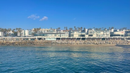 Obraz premium Coastal buildings and palm trees along the beachfront under clear blue sky