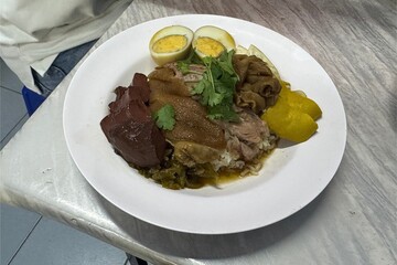 Thai style pork leg rice dish with egg on table