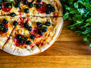Pizza pepperoni with mozzarella cheese and black olives on wooden table