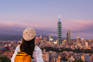 Young female tourist enjoying panoramic view of Taipei city skyline at sunset, travel concept