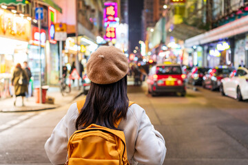 Young woman tourist walking in the Mong Kok night market in Hong Kong