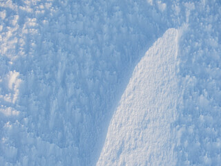 Beautiful winter background with snowy ground. Natural snow texture. Wind sculpted patterns on snow surface.